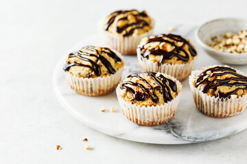 Homemade hazelnut muffins with chocolate topping on a marble board. Selective focus.