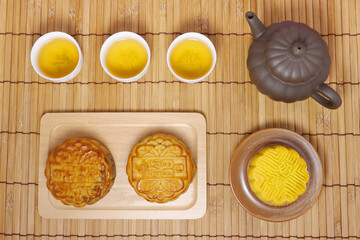 Teapot and moon cake on bamboo table.  Concept for Mid-Autumn Festival or Moon Festival, a traditional holiday in East Asia. Chinese words on moon cake are 