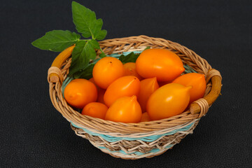 Yellow tomato heap in the wooden bowl