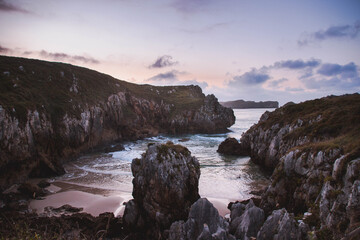 Fotografía al atardecer rosado en una playa con rocas de un viaje a Asturias