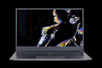 laptop with a broken screen in color spots and cracks isolated on black background close up front view