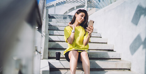 Obraz premium Young woman with smartphone on stairs taking funny selfie