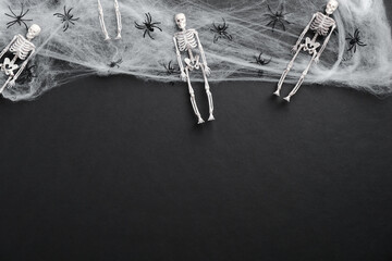 Black halloween background with skeletons, spider web, spiders. Halloween banner mockup. Flat lay, top view, overhead.