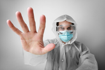 Close-up of young doctor in special suite holds a face mask as preventive measure of coronavirus COVID-19 give his hand.