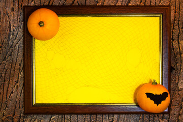 Halloween. Wooden frame with web, orange pumpkins, bat and yellow paper blank space for text on...
