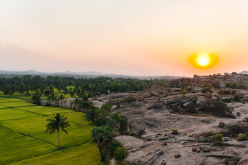 Awesome sunset close to rice fields and palm trees in Hampi Island, India, Karnataka.