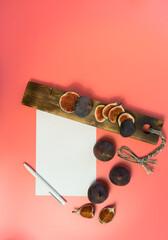 work table with blank sheets and pen, sliced fresh juicy figs, pink background. Planning concept, top view, flat lay.