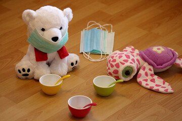 Children play at home in a period of pandemic and put a medical mask on the teddy bear