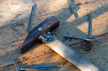 Old vintage hammer and nails on a wooden background, close-up, selective focus.