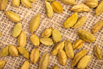 Cardamom scattered on coarse burlap, close-up, selective focus.