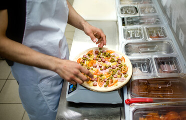 
the chef prepares pizza. weighs the ingredients