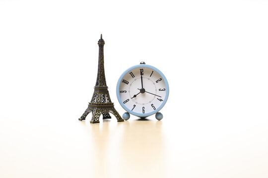 Alarm clock and Eiffel tower ornament on white background 
