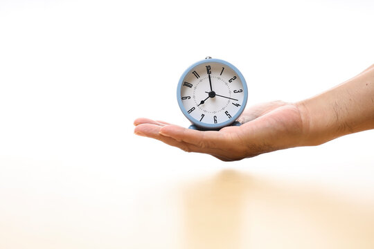 Cropped hand and an alarm clock on the palm on white background 