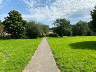 Footpath, leading through a large grass field, with old trees next to Meanwood Road, leading to local housing in, Leeds, Yorkshire, UK