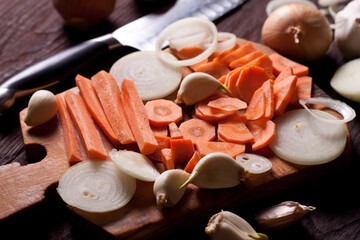 Cutting board with chopped vegetables, carrots, onions, garlic. Cooking concept, cuisine, dish, recipe.
