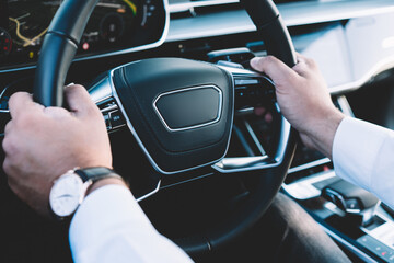 Cropped selective image of male hands steering automotive car enjoying travel getaway in luxury...