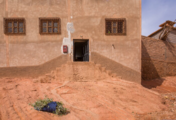 A bushel of branches lies in front of a traditional home in the Valley of Roses region of Morocco
