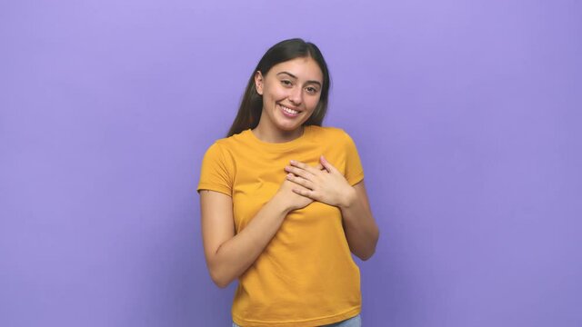 Young caucasian woman has friendly expression, pressing palm to chest love concept