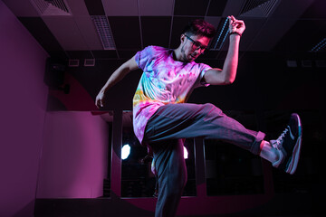 Professional break dancer in motion, practicing modern hip-hop dance in pink neon light
