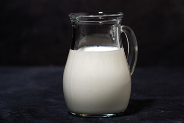 jug with fresh milk on a black background, closeup