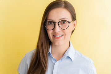 Portrait of tatar female student wearing glasses smiling isolated on yellow background