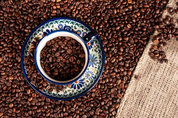 Beans of coffee on the table in cup. - obrazy, fototapety, plakaty