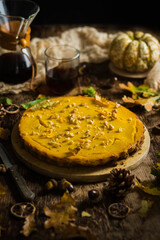 Pumpkin pie with zest of oranges and nuts on rustic background.