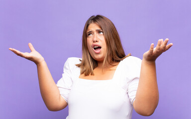 young blonde woman shrugging with a dumb, crazy, confused, puzzled expression, feeling annoyed and...