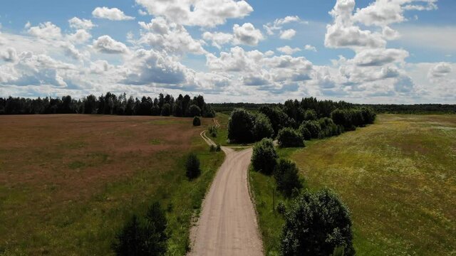 Crossroads two gravel roads. Bushes in summer field. Aerial view countryside