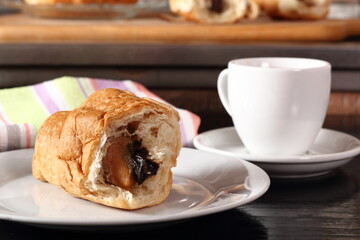 Croissant with cocoa and peanut fillings and coffee cup