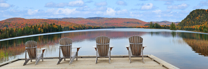 Wooden armchairs on Lake Monroe shore and autumn colors in Mont Tremblant National Park, Quebec