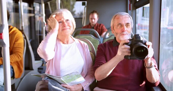 Senior couple sightseeing and taking pictures with camera inside bus