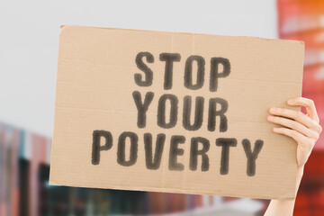 The phrase " Stop your poverty " on a banner in men's hand with blurred background. Money. Earnings. Poor. Poorness. Life. Business. Job. Salary