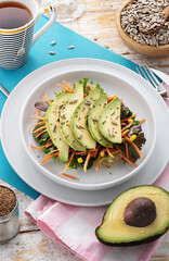 vegan breakfast with toast avocado lettuce, carrot, sesame and sunflower seeds and a cup of tea