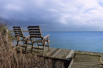 Naklejka na ściany i meble Calm down at the coast - empty chairs at the waterfront