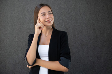 Beautiful woman wearing business suit over grey background. Pointing to head with one finger, great idea or thought, good memory