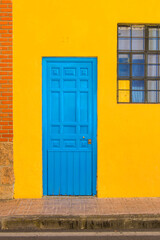 blue metal door on a yellow facade with part of a window