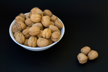 bowl with walnuts and three outside, isolated on black background