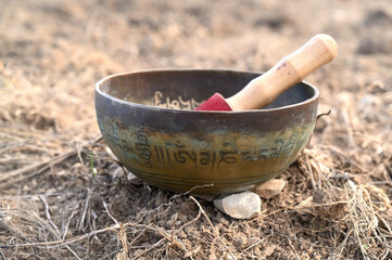 A tibetan singing bowl in a natural environment. Translation of mantras : transform your impure body, speech, and mind
