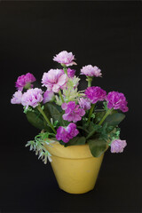 pot with artificial lilac and pink flowers, isolated on black background