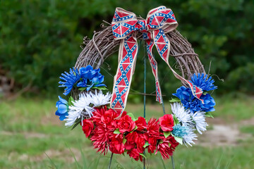 A wreath of blue, white and red flowers with Confederate flag themed ribbons. This wreath was...