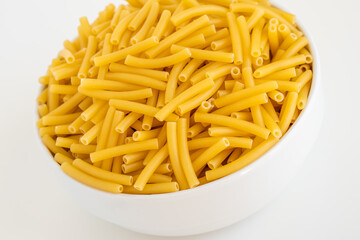 Raw dry uncooked Macaroni pasta spaghetti noodle on white bowl wooden background for basil tomato pesto sauce Homemade Italian food organic whole wheat vegan spaghetti for a healthy meal