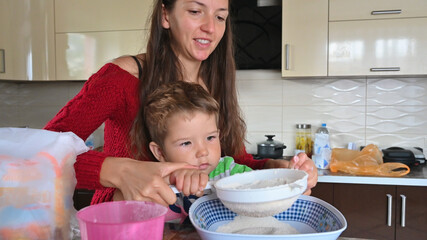 Obraz na płótnie Canvas little child helps mom cook in the kitchen