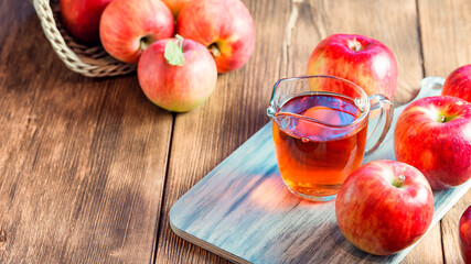 Processing of an agricultural crop of red and green apples. Home canning, healthy diet vegetarian food. Apple cider vinegar, juice, cider in a glass jar next to ripe fruit
