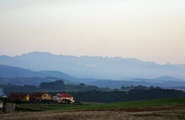 Fototapeta premium Precioso paisaje con casas y montañas al atardecer 