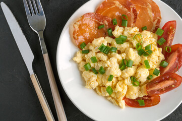 scrambled eggs with tomatoes on a white plate.