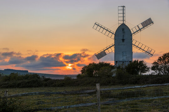 Sun setting behind Ashcombe Windmill from Kingston Ridge south downs near Lewes east Sussex south east England