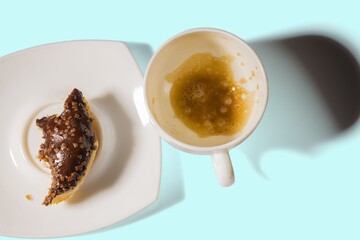 Close up view of empty cup with rest of coffee and piece of chocolate  donut. Food and drink concept.