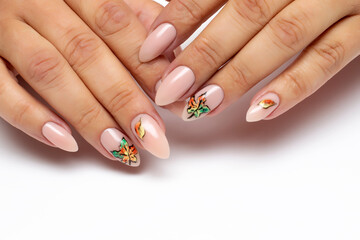 Autumn gel nail design. Nude manicure with painted maple leaves on long almond, oval nails close-up...