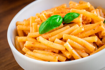 Healthy organic Italian macaroni homemade fresh pasta spaghetti noodles cook with basil tomato garlic pepper sauce with vegan vegetarian recipe in white bowl on wooden vintage table